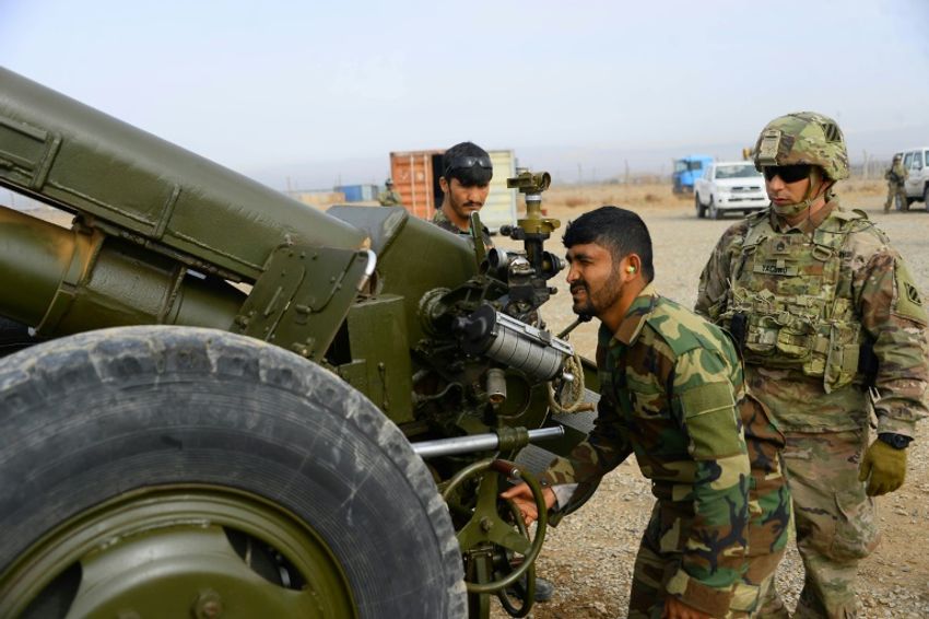 جندي من قوات حلف شمال الأطلسي يراقب جنديا أفغانيا وهو يطلق قذيفة مدفع في هيرات