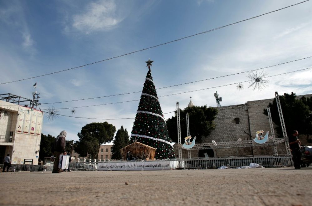 A man walks past a Christmas tree on Manger Square near the Church of the Nativity, revered as the site of Jesus Christ's birth, on December 16, 2015 in the West Bank city of Bethlehem