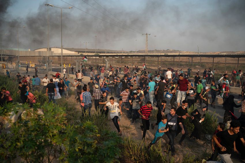 FILE- Palestinian protesters run from tear gas fired by Israeli soldiers during a protest at the entrance of Erez border crossing between Gaza and Israel, in the northern Gaza Strip, Tuesday, Sept. 4, 2018.