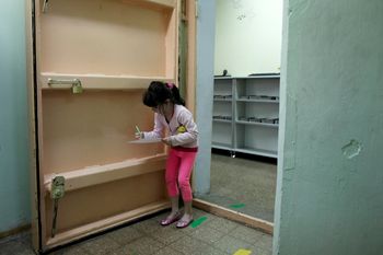 An Israeli girl attempts to write on a piece of paper as she leaves a bomb shelter after an air raid siren drill at the Hashalom school in Jerusalem, Wednesday, May 26, 2010. Air raid sirens have sounded across Israel as part of a massive air raid drill. 