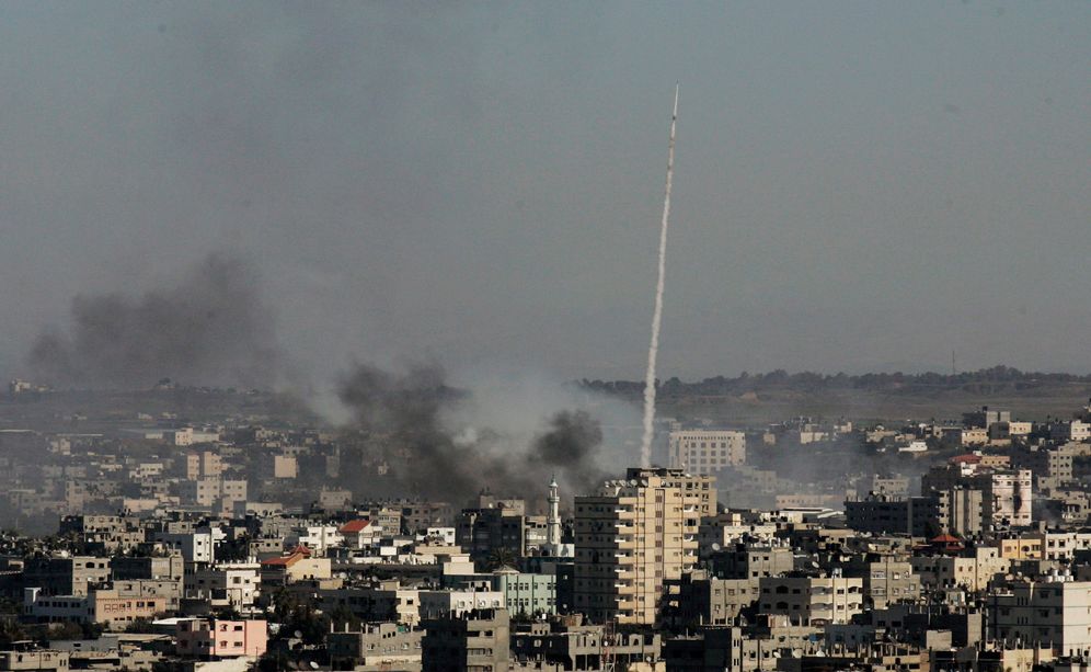 FILE - In this Tuesday, Jan. 6, 2009 file photo, a rocket fired by Palestinian militants at southern Israel leaves a thin trail of white smoke, as smoke caused by explosions from Israeli forces' operations rises from buildings on the outskirts of Gaza Cit