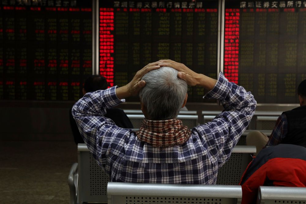 An investor reacts near boards displaying stock market prices in Beijing, China, on December 6, 2018.