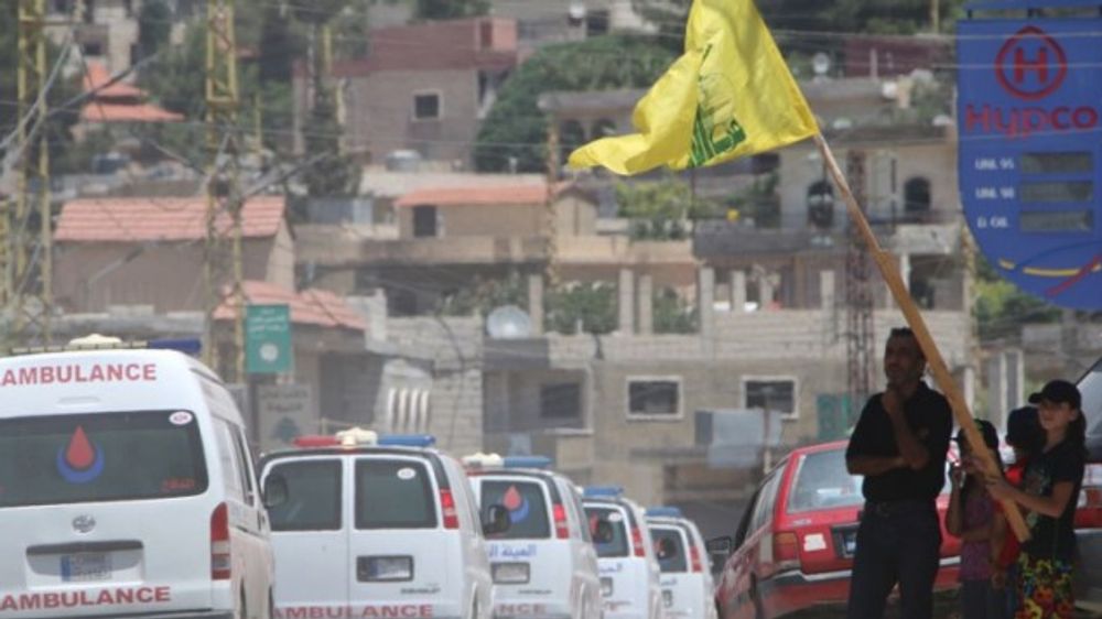 People wave a flag of the Lebanese Shiite Hezbollah movement as the group's ambulance convoy drives past, carrying bodies of fighters killed in week-long clashes in the Jurud Arsal border region, as part of a ceasefire deal.