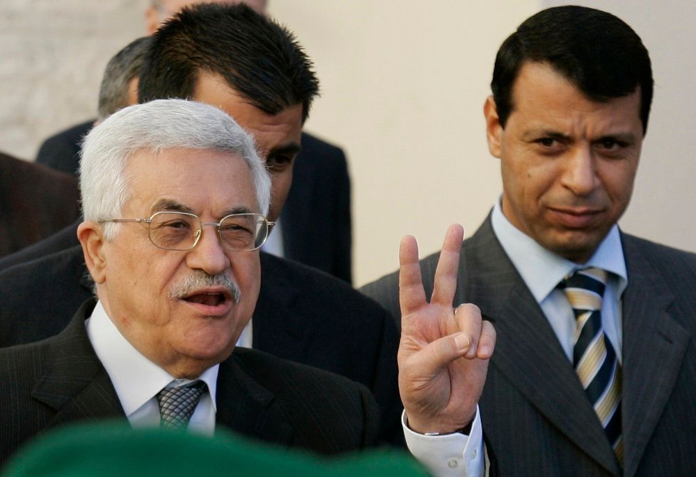 في هذه الصورة الأرشيفية الملتقطة في 18 كانون الأول (ديسمبر) 2006، يظهر رئيس السلطة الفلسطينية محمود عباس، على اليسار، يرفع يده بعلامة V بينما ينظر زعيم فتح آنذاك، محمد دحلان، في مدينة رام الله بالضفة الغربية.