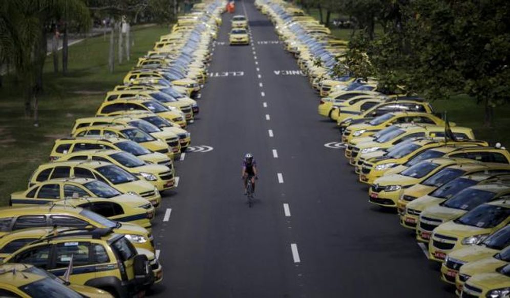 A man rides his bicycle between taxis parked on the street during a protest against the online car-sharing service Uber in Rio de Janeiro, Brazil July 24, 2015