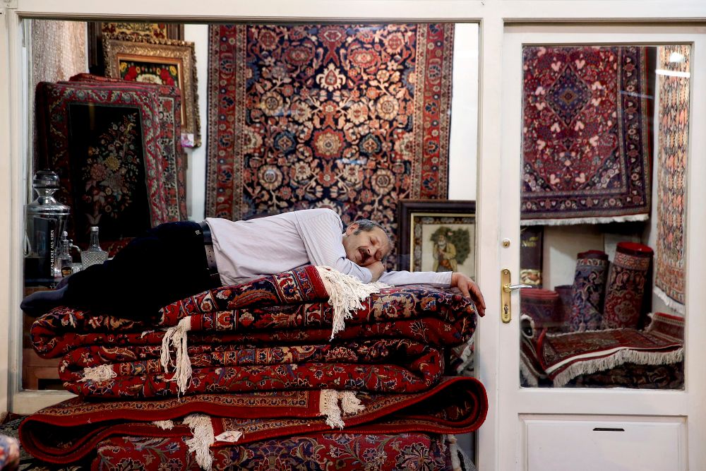 A carpet seller takes a nap at the carpet market in the old main Bazaar in Tehran, Iran, Monday, July 23, 2018.