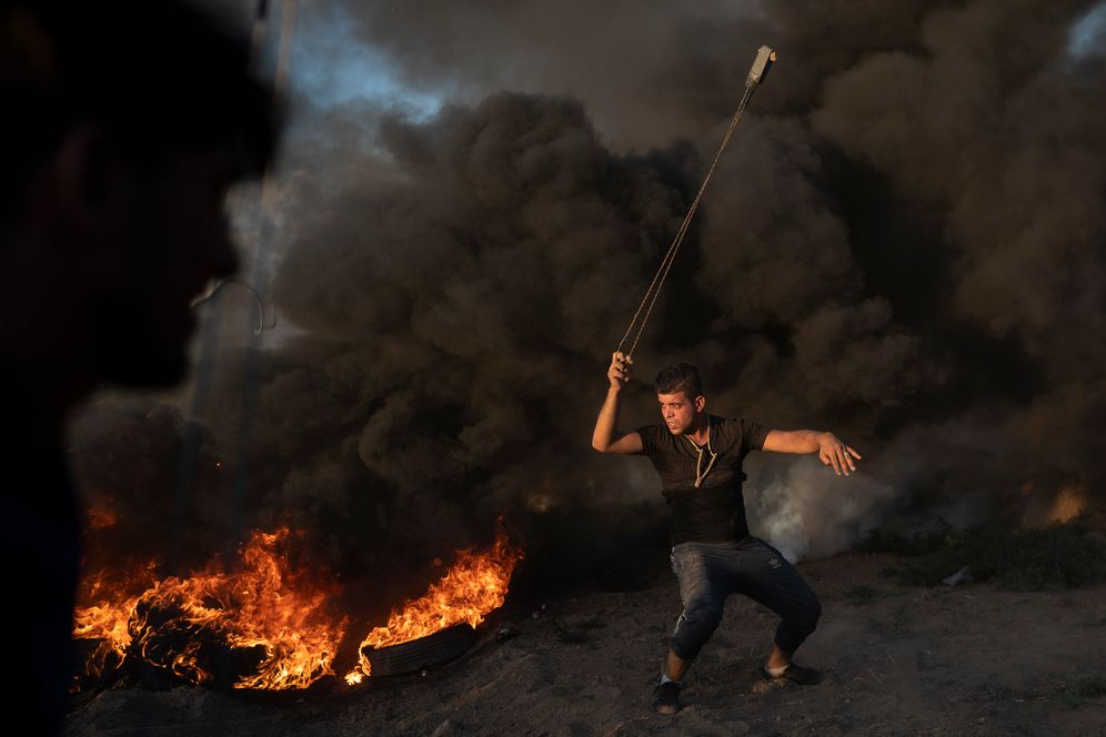 A Palestinian protester hurls stones during a protest at Gaza Strip's border with Israel, east of Gaza City, Friday, Sept. 7, 2018.