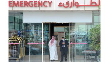 A man, wearing a mouth and nose mask, checks his phone as he leaves the hospital's emergency department on April 27, 2014 in the Saudi capital Riyadh