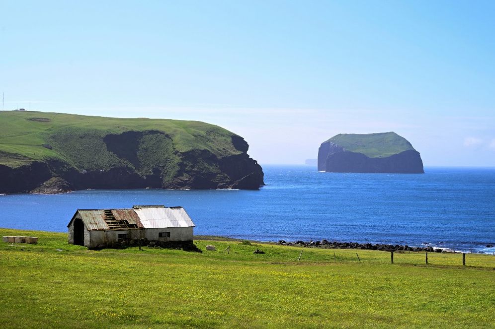 An old barn near the Puffin Lookout and the island of Sudurey (back R) on Heimaey on the Icelandic archipelago of Vestmannaeyjar, Westman Islands.