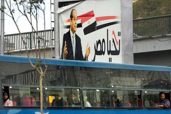 مصريون يسافرون على متن حافلة عامة تحت لافتة للرئيس المصري عبد الفتاح السيسي باللغة العربية تقول "تحيا مصر" في القاهرة، مصر، الخميس 12 يناير 2023.