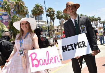 Cosplayers hold Barbenheimer signs outside the convention center during San Diego Comic-Con International in San Diego, California, on July 21, 2023.