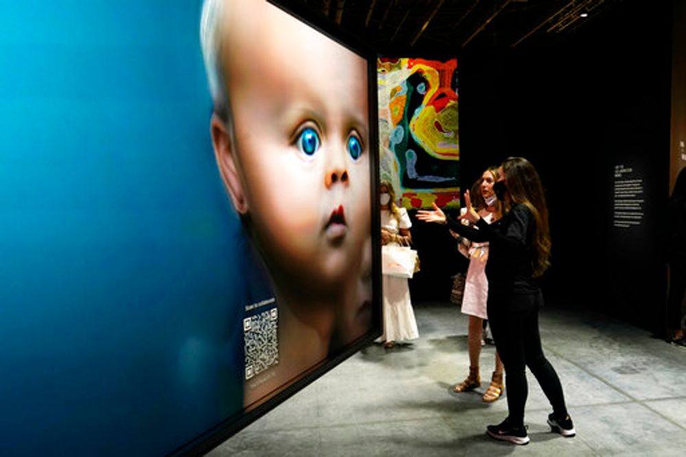 People look at NFT artwork of the Tezos exhibition at Art Basel Miami Beach in Florida, United States, November 30, 2021.