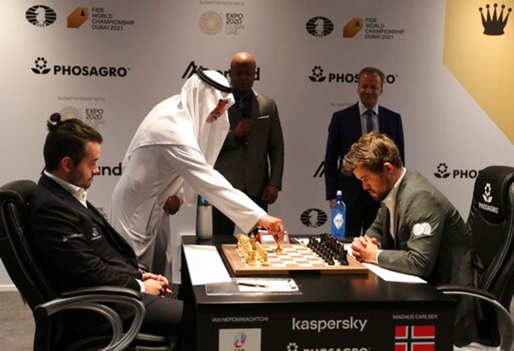 Sheikh Nahyan bin Mubarak Al Nahyan makes the starting move of game five between Norway's World Chess Champion Magnus Carlsen (R) and Ian Nepomniachtchi of Russia, during the FIDE World Championship in Dubai, United Arab Emirates, December 1, 2021.