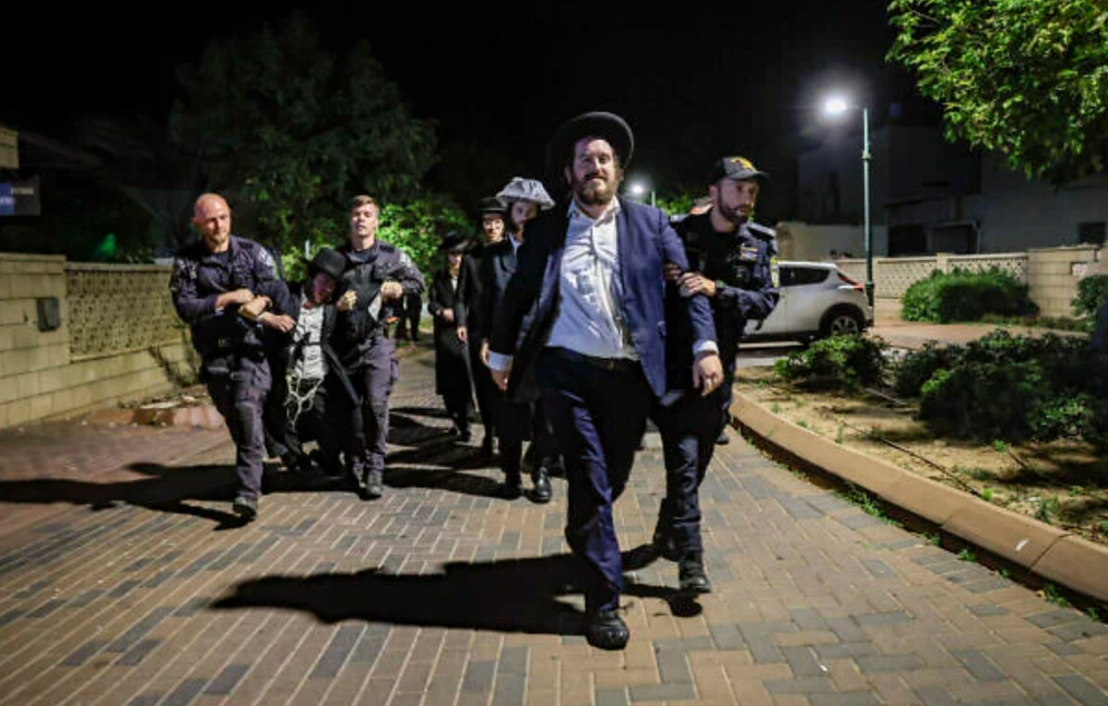 Tsafrir Abayov/Flash90 Des hommes juifs orthodoxes manifestent contre l’incarcération d’étudiants de yeshiva ayant échappé à la conscription, devant le domicile du chef de la police militaire, le général de brigade Yuval Yamin, à Ashkelon, le 14 mai 2026.