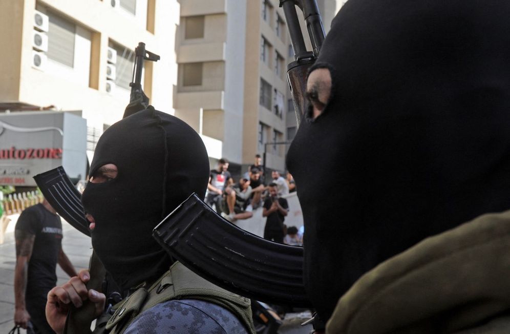 Masked Shi'ite fighters from Hezbollah and Amal movements walk with Kalashnikov assault rifles amidst clashes in the area of ​​Tayouneh, in the southern suburb of the capital Beirut, on October 14, 2021.