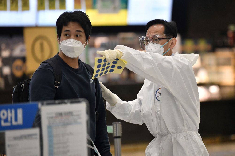 A staff member (R) wearing protective equipment guides a traveler at the arrival hall of Incheon International Airport on November 30, 2021, amid growing concerns about the omicron Covid-19 variant.