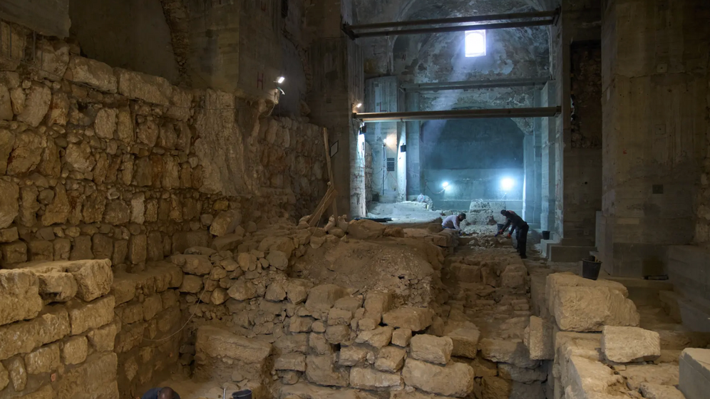 Des ouvriers de l'Autorité des antiquités d'Israël nettoient une partie d'un site de fouilles où, selon l'institution, une muraille datant de la période hasmonéenne, vers la fin du IIe siècle avant notre ère, a été mise au jour sous le musée de la Tour de David, dans la vieille ville de Jérusalem, le 8 décembre 2025.