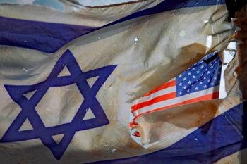 A U.S. flag is seen through a hole torn in an Israel national flag, near the southern Israeli town of Sderot.