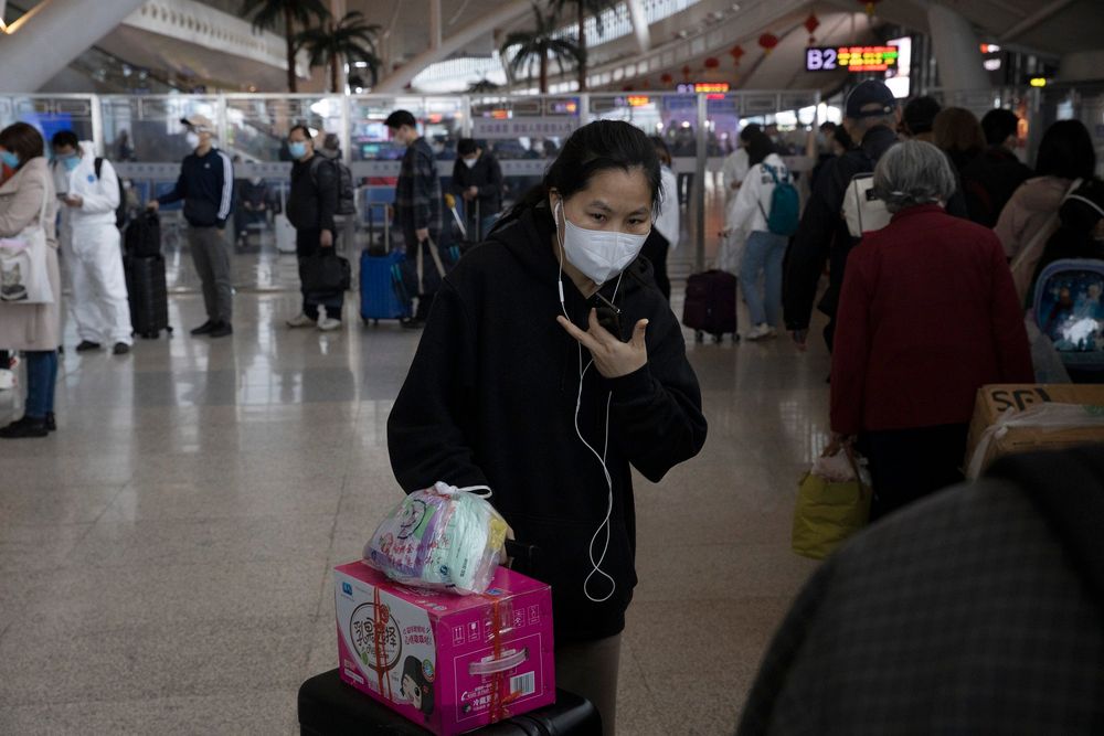 FILE - A woman talks on her phone as she lines up to board a high speed train leaving from the train station in Wuhan in central China's Hubei province on April 19, 2020
