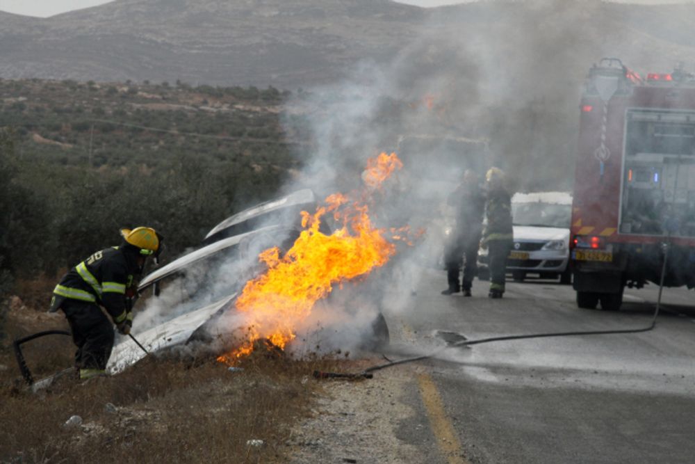 Les pompiers éteignent le feu d'une voiture en feu appartenant à des Israéliens près du village de Tuqua en Cisjordanie