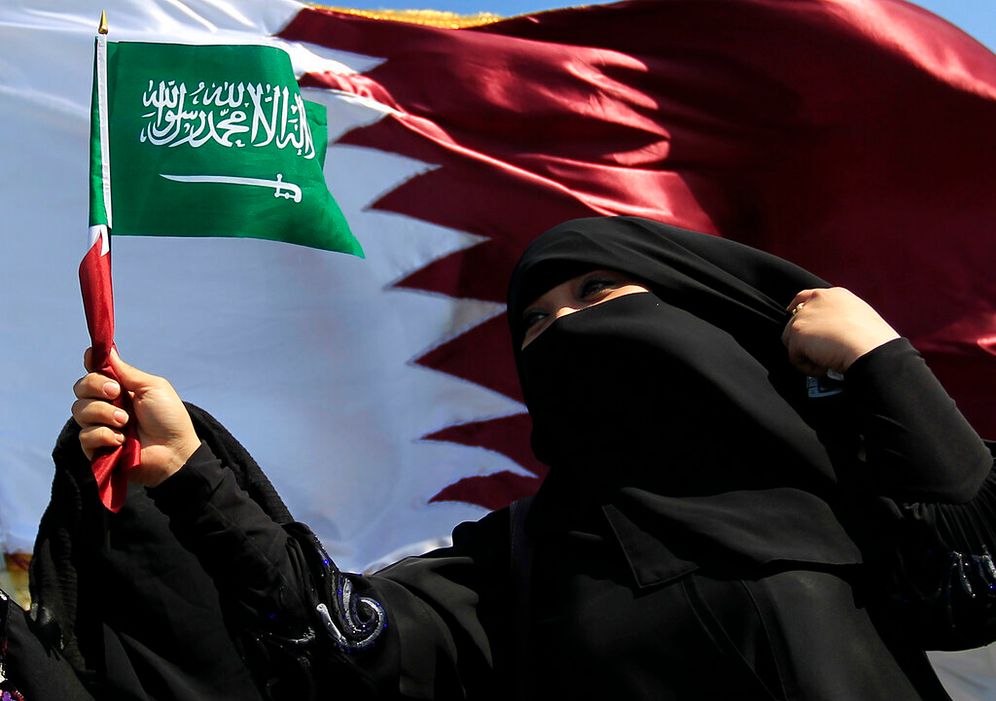 امرأة قطرية تلوّح بعلم المملكة العربية السعودية بينما يرفرف علم قطري كبير خلفها، وذلك خلال الاستعدادات لبطولة كأس آسيا لكرة القدم في الدوحة، قطر، يوم الاثنين 3 يناير/كانون الثاني 2011.