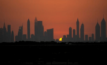 Le soleil se couche derrière les tours de l'autoroute Sheikh Zayed, à Dubaï, aux Émirats arabes unis, le dimanche 18 juin 2023.