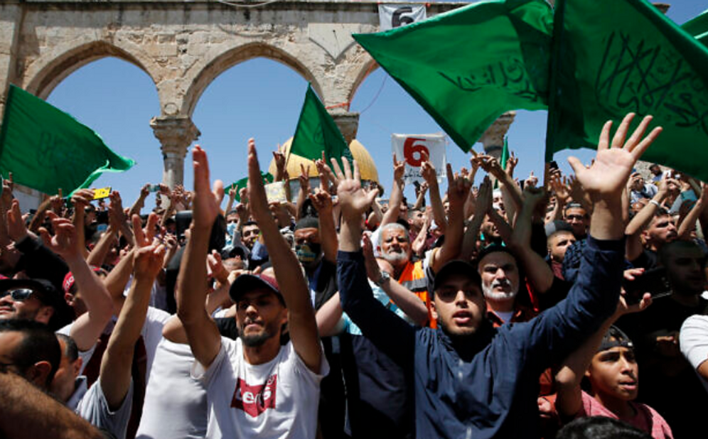 Palestinians wave Hamas flags after afternoon prayers on the Temple Mount in Jerusalem's Old City on the last Friday of the Muslim holy month of Ramadan, May 7, 2021.
