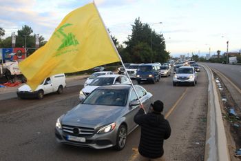 Hezbollah supporter waves a flag on the road between Sidon and Tyre