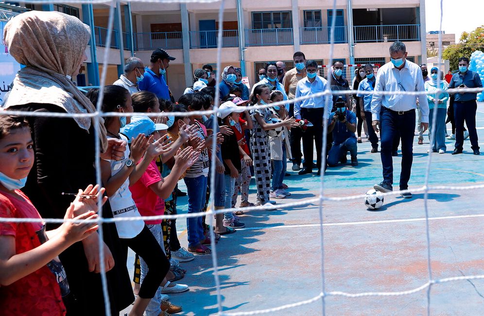 Philippe Lazzarini (R), commissioner-general of UNRWA, plays with a soccer ball in front of students in Gaza's Shati refugee camp.