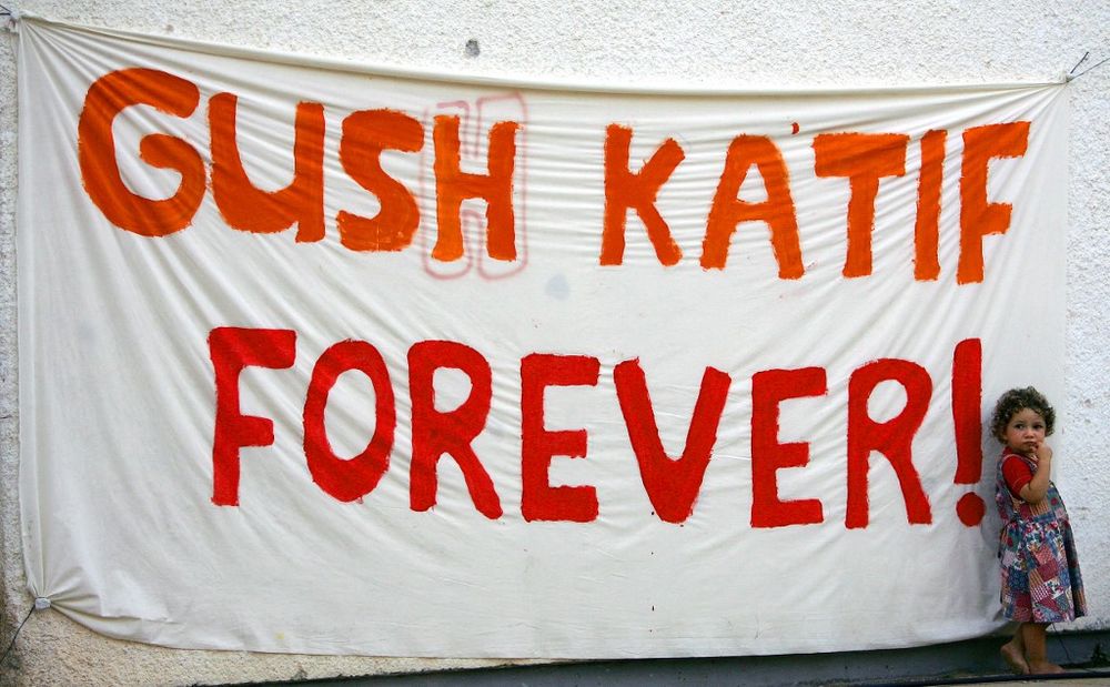 A young child stands next to a banner with the inscription "Gush Katif Forever" at the Gaza Strip settlement of Nezer Hazani in the Gush Katif bloc, Gaza Strip, August 17, 2005.