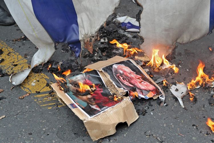 An Israeli flag and a cartoon picture of US President Joe Biden on fire in Tehran, Iran, on April 29, 2022.