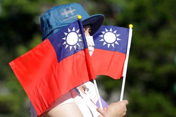A woman holds up Taiwan national flags during National Day celebrations in front of the Presidential Building in Taipei, Taiwan, on October 10, 2021.