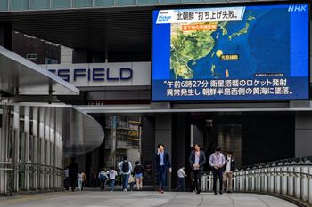 Pedestrians walk past a large video screen showing a map of the region after North Korea launched a spy satellite that crashed into the sea.