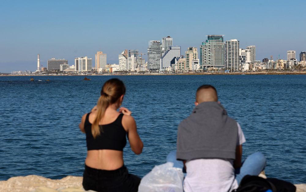 A young couple share a picnic in front of a view of the Tel Aviv skyline, in the Israeli coastal city, on February 15, 2021.