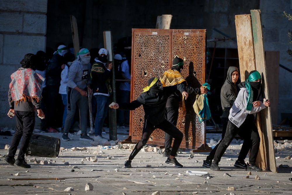 Des émeutiers palestiniens lancent des pierres contre les forces de sécurité israéliennes lors d'affrontements pendant le mois sacré du Ramadan sur le mont du Temple dans la vieille ville de Jérusalem, le 15 avril 2022