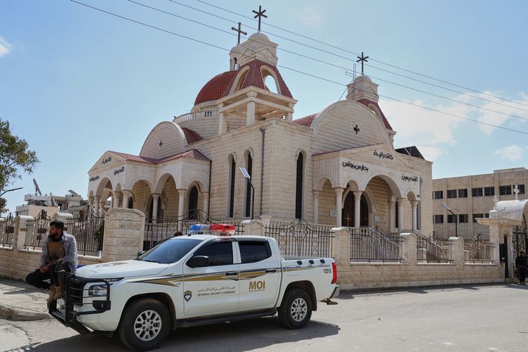 يجلس أحد أفراد قوات الأمن الداخلي السورية على متن سيارة متوقفة خارج كنيسة في بلدة السقيلبية ذات الأغلبية المسيحية، غرب حماة، سوريا، يوم السبت 28 مارس/آذار 2026، في أعقاب أعمال عنف اندلعت خلال الليل.