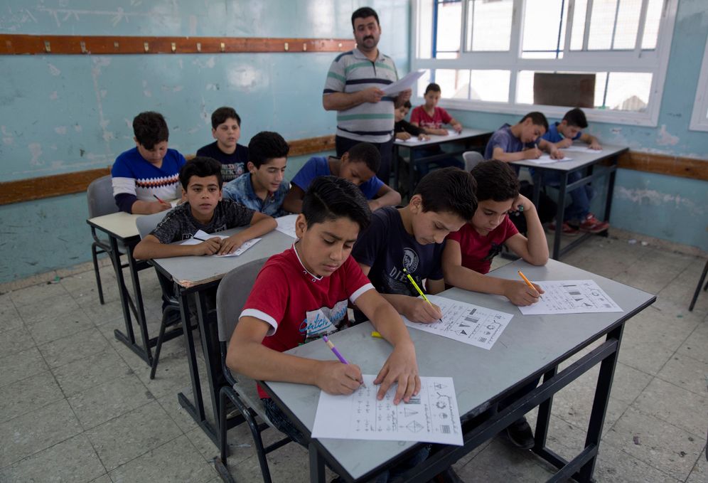 A teacher supervises while Palestinian children attend a final exam during the last day of the school year in Hebron on May 26, 2019.
