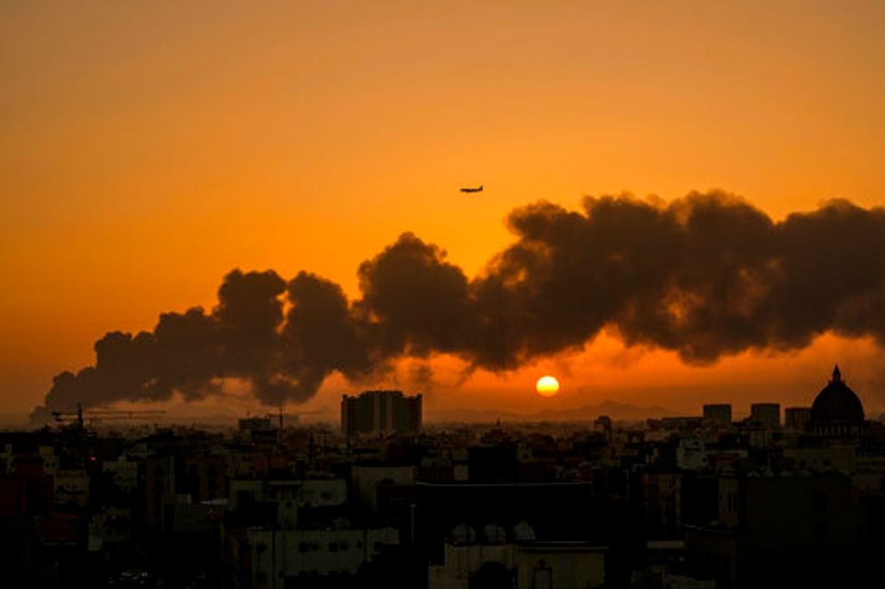 A passenger airplane flies over a smoldering fire at a Saudi Aramco oil depot after a Yemen Houthi rebel attack in Jeddah, Saudi Arabia, March 26, 2022.