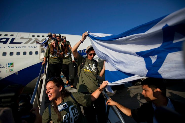 Des immigrants juifs des États-Unis brandissent un drapeau israélien à leur arrivée à l'aéroport Ben Gurion près de Tel Aviv, en Israël.