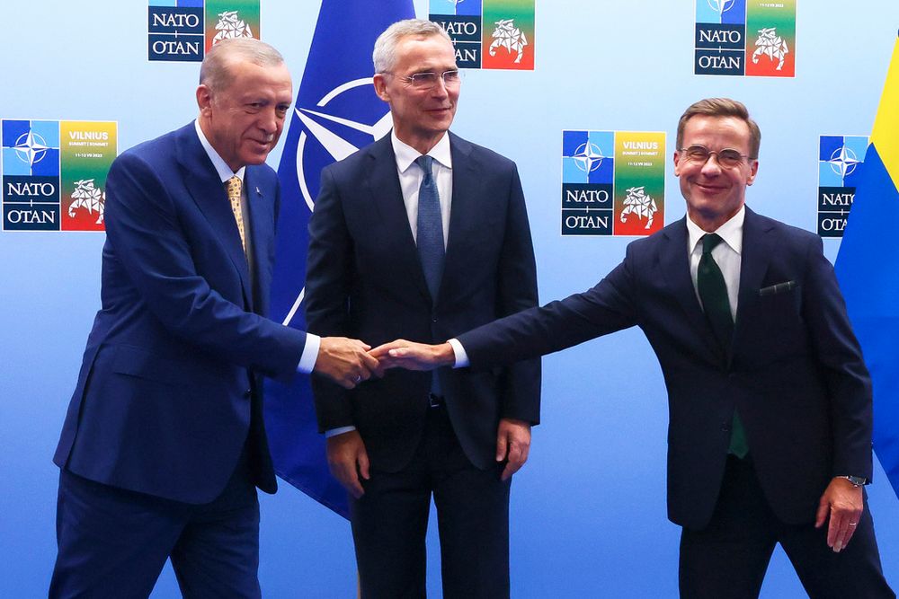 Turkey's President Recep Tayyip Erdogan (L) shakes hands with Sweden's Prime Minister Ulf Kristersson (R) next to NATO Secretary chief Jens Stoltenberg in Vilnius, Lithuania.