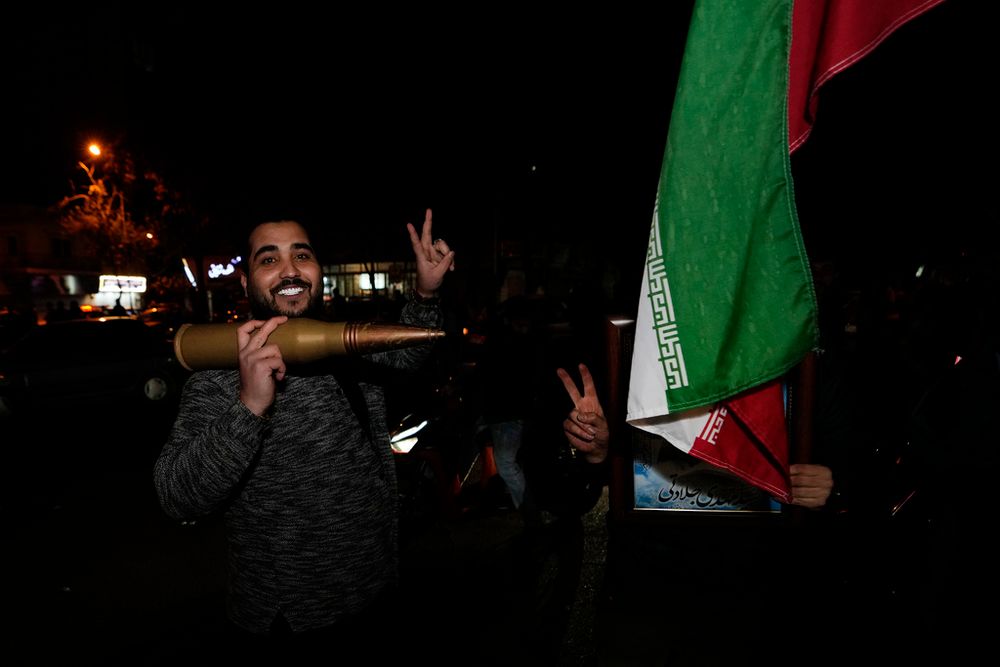 Demonstrators gesture as they hold an Iranian flag and a large munition during an anti-Israeli gathering in Tehran, Iran.