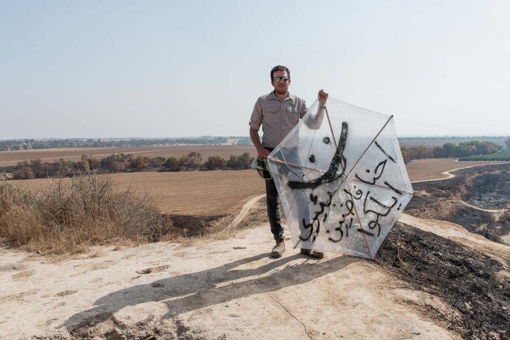 A man holds a kite from Gaza in a burnt area of Besor Stream in Tel Gama, near Kibbutz Re'im, near the border with the Gaza Strip, on July 25, 2018