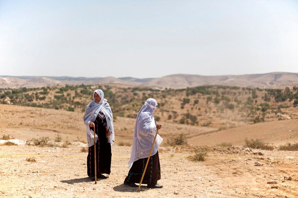 AP Photo/Ariel Schalit, File Two Bedouin women walk on a hill top in the Negev desert, southern Israel.