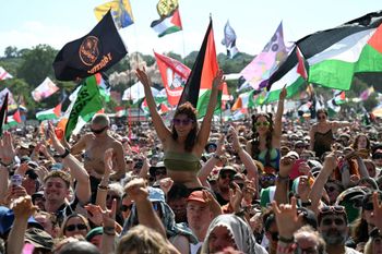 Festivalgoers watch as Irish rap band Kneecap perform at the West Holts stage on the fourth day of the Glastonbury festival in Somerset, south-west England, on June 28, 2025.