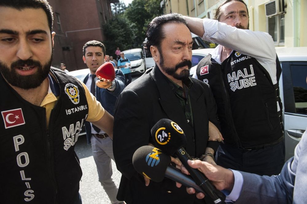 Turkish police officers escort televangelist and leader of a sect, Adnan Oktar (C) in Istanbul, Turkey, as he is arrested on fraud charges.