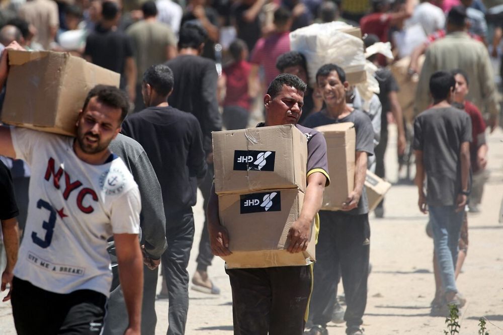 People carry boxes of aid supplies from the Gaza Humanitarian Foundation (GHF) in the central Gaza Strip on May 29, 2025.