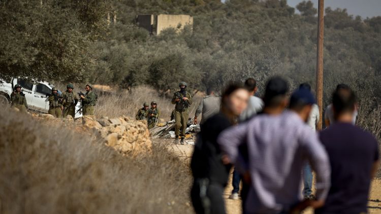 File photo showing IDF soldiers and Israeli settlers in the West Bank village of Qusra