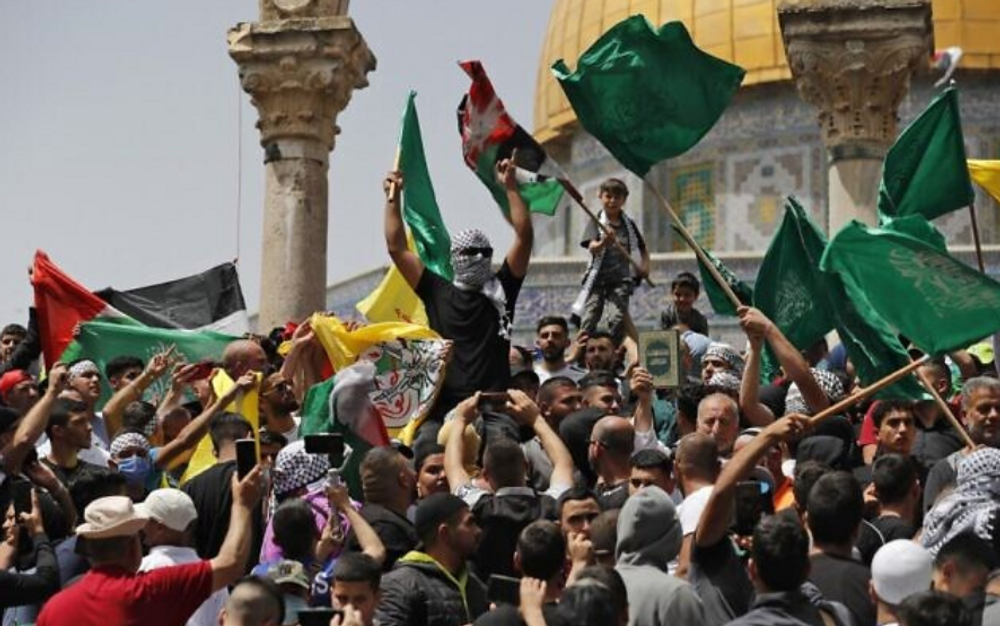 Des Palestiniens brandissent des drapeaux palestiniens et islamiques lors d'un rassemblement à la mosquée Al-Aqsa sur le Mont du Temple à Jérusalem, après la dernière prière du vendredi du mois sacré musulman du Ramadan, le 29 avril 2022.