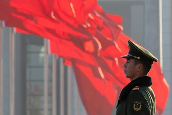 شرطي صيني الى جانب علم الصين - صورة ارشيفية