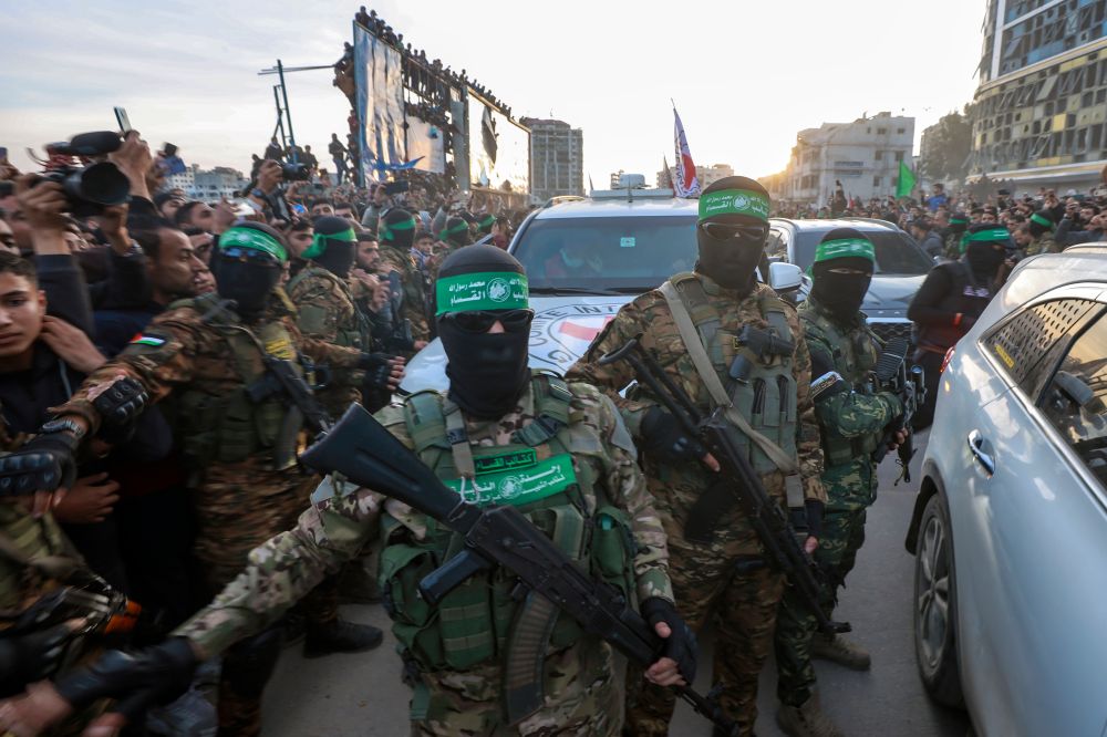 Hamas terrorists escort a Red Cross vehicle to collect Israeli hostages released after a ceasefire agreement between Israel and Hamas took effect